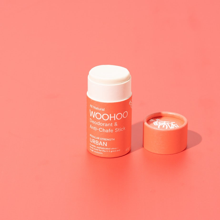 Image of opened Urban Natural Deodorant Stick with cardboard cap next to the product on a deep rose background