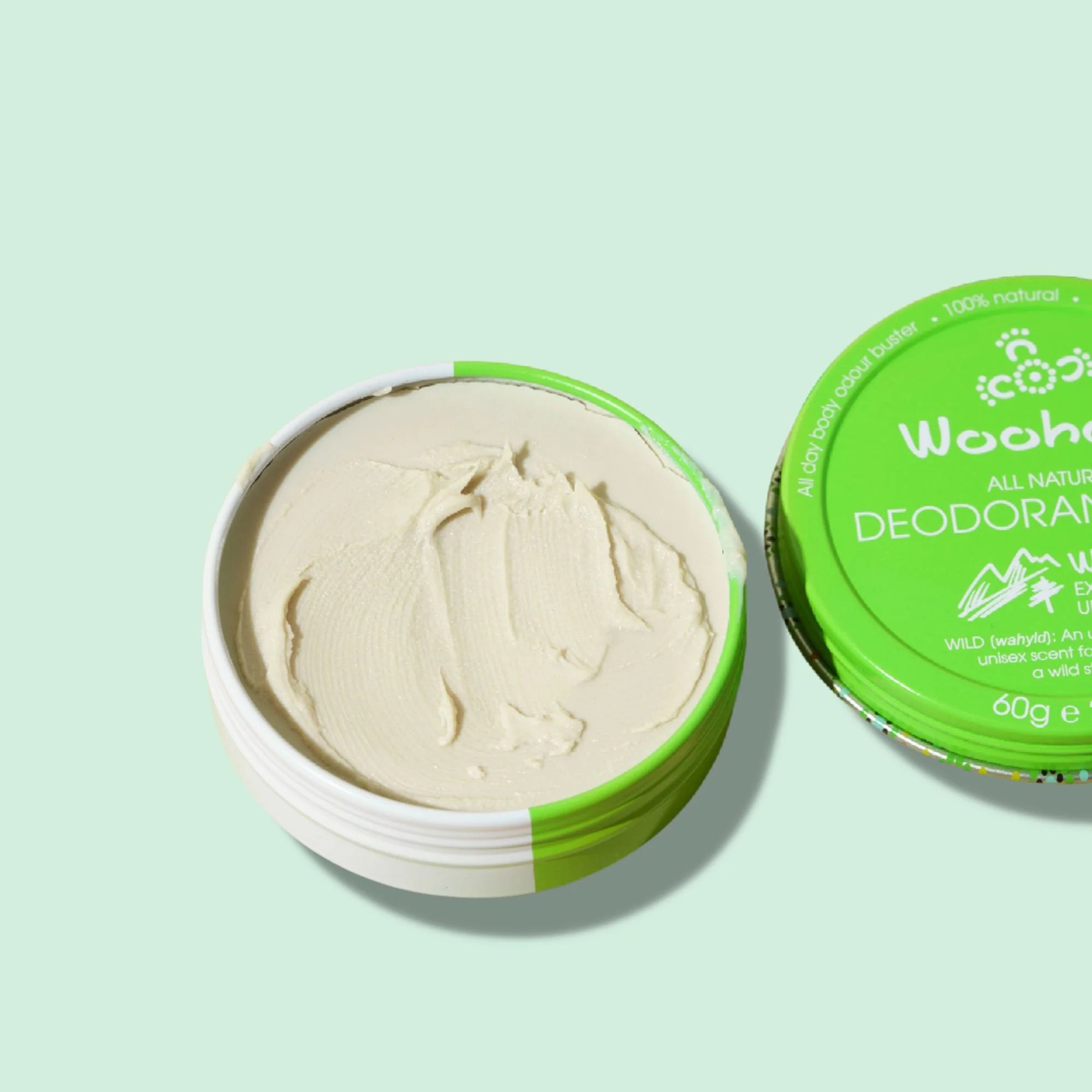 Image of an opened Woohoo Wild Natural Deodorant Paste tin with cap next to it on a light green background