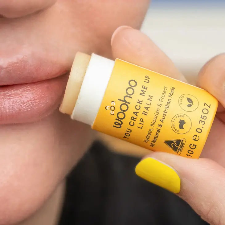 Image of an opened Woohoo You Crack Me Up! Lip Balm held in a hand next to lips 